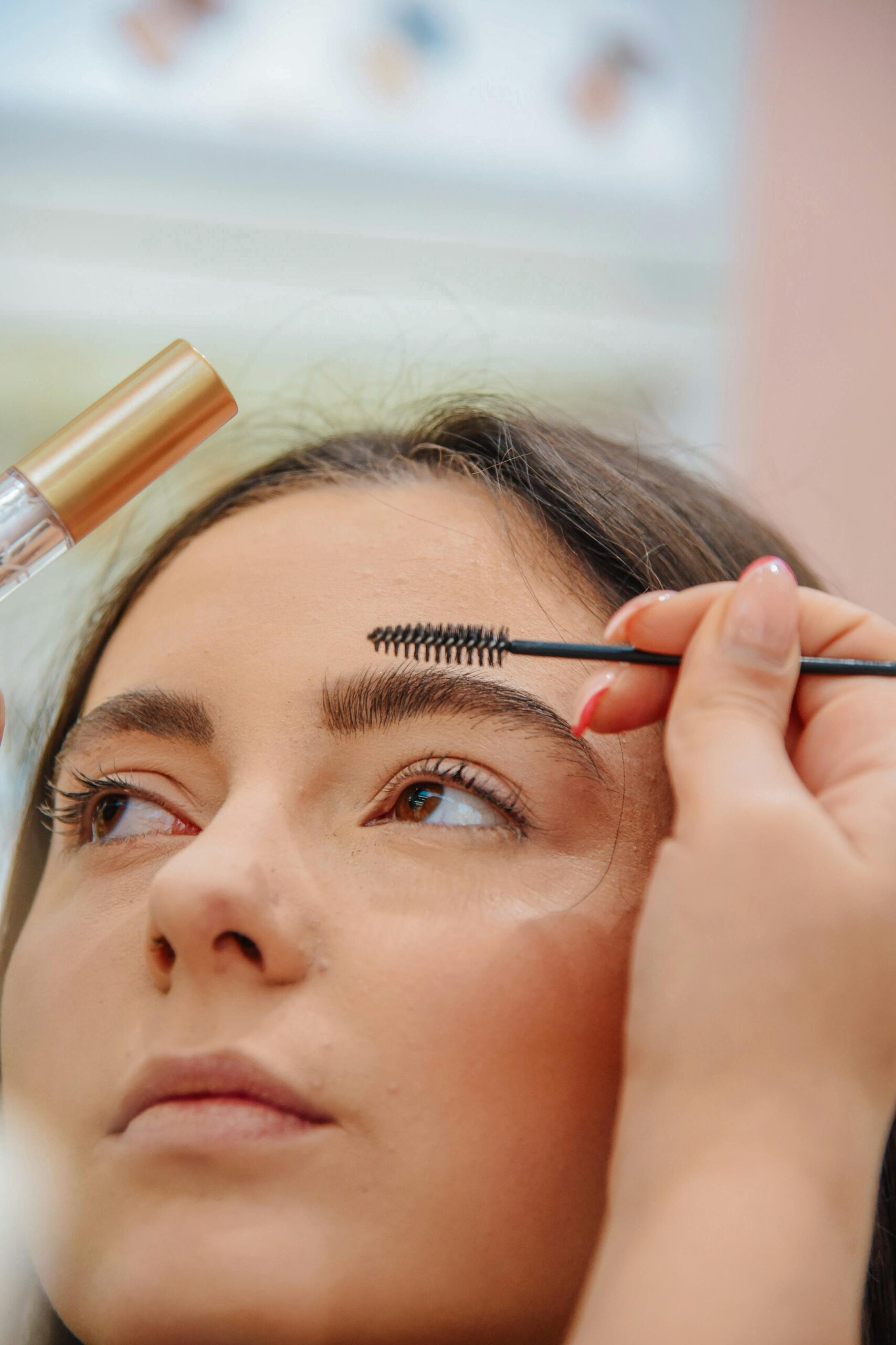 Makeup artist applying eyebrow gel to a young woman