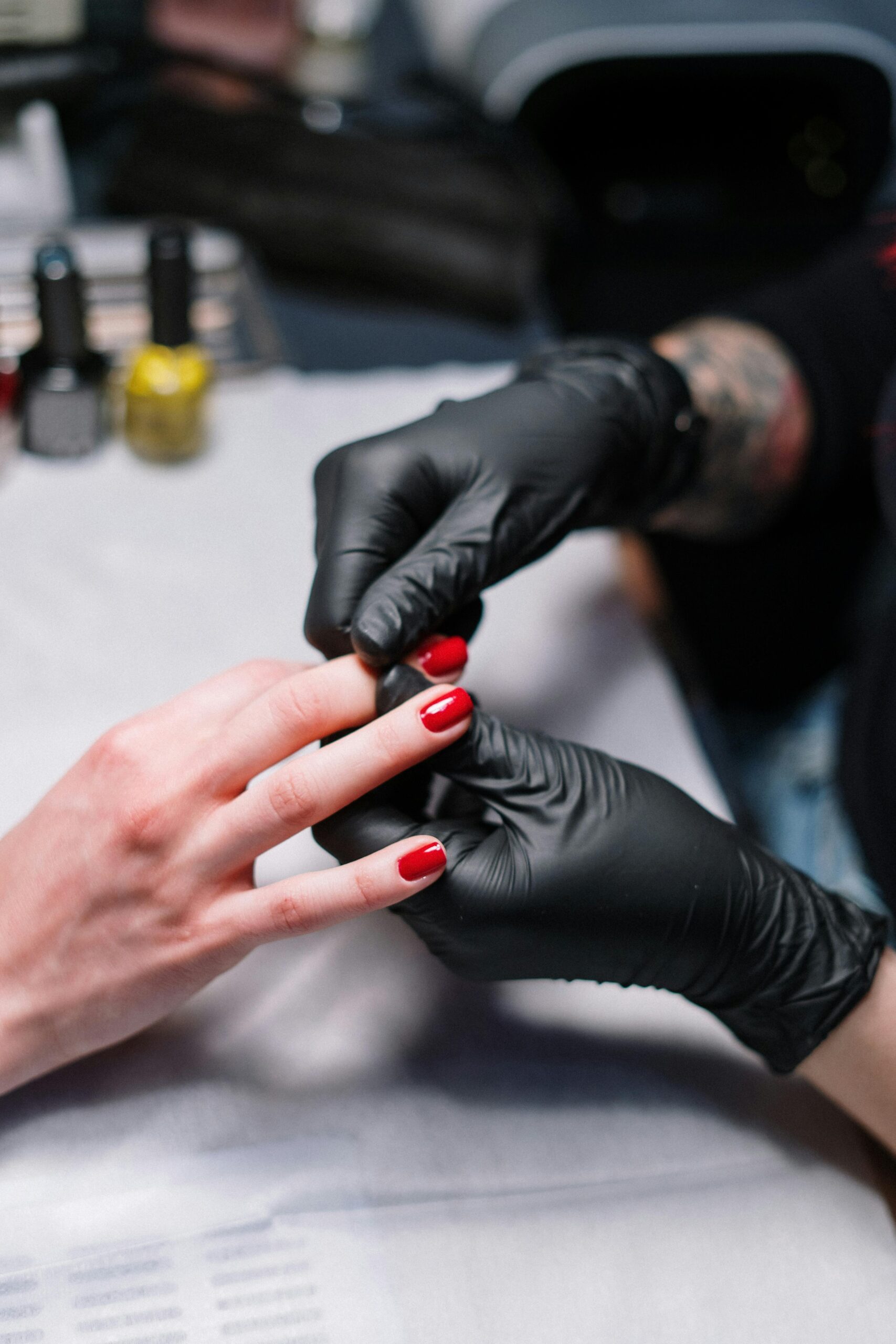 Close-up of a manicurist applying red nail polish in a salon.